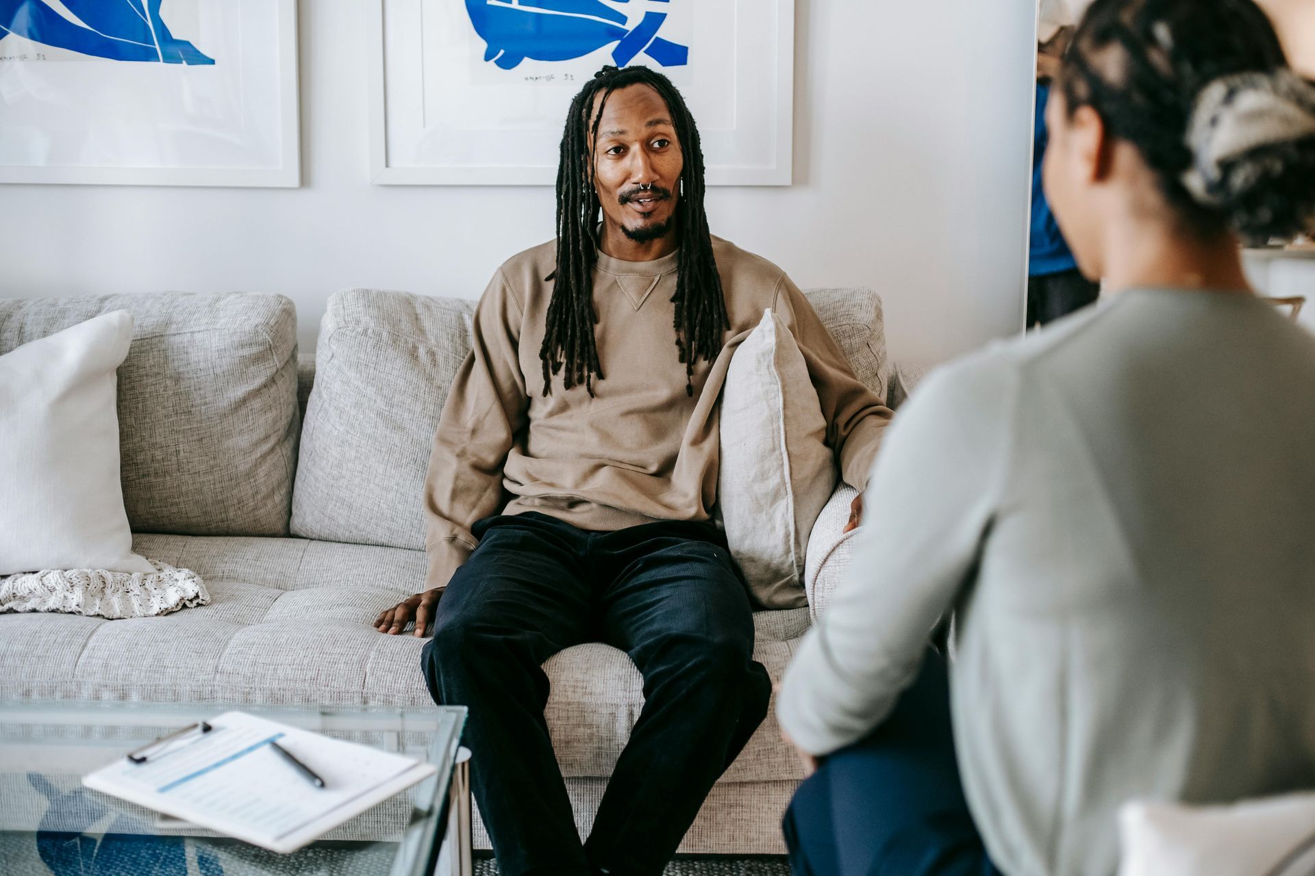 A man is sitting on a couch talking to a woman.