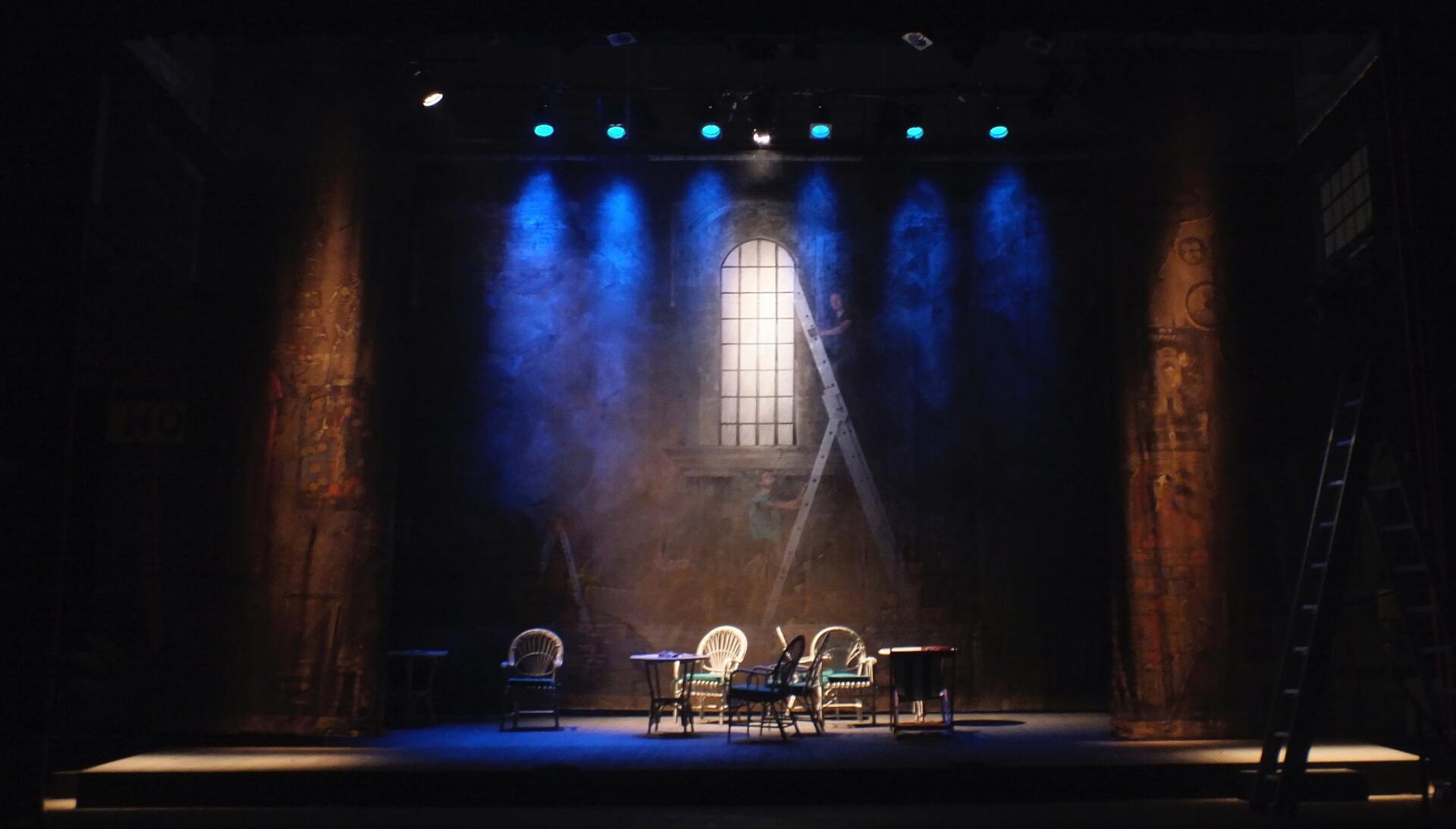 A stage set for a play with chairs and a piano.