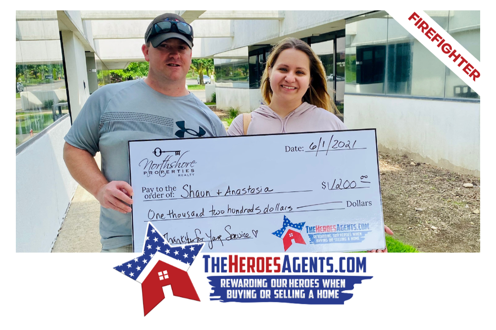 A man and a woman are holding a large check in front of a building.