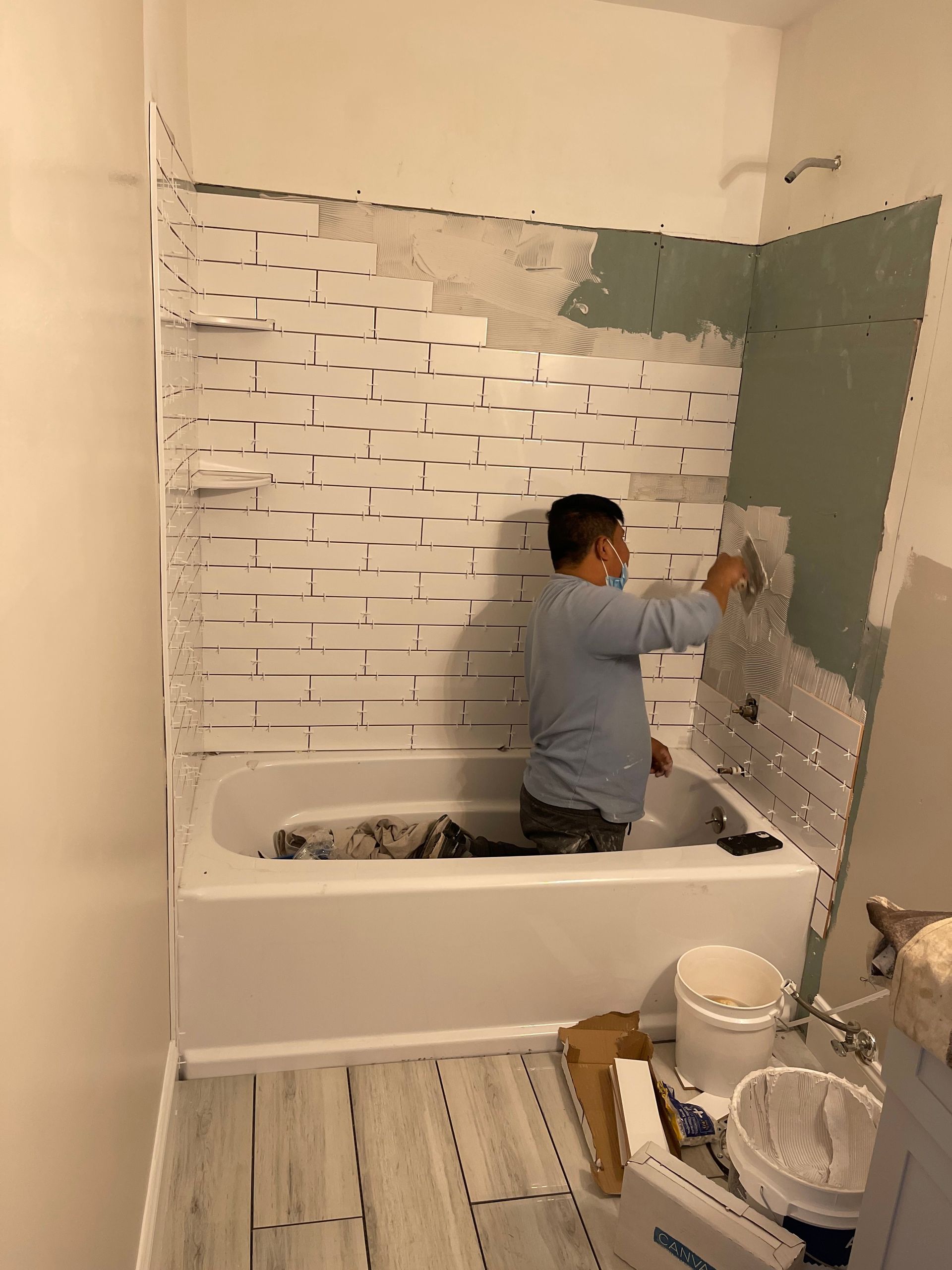 Person installing white tile in a bathroom renovation
