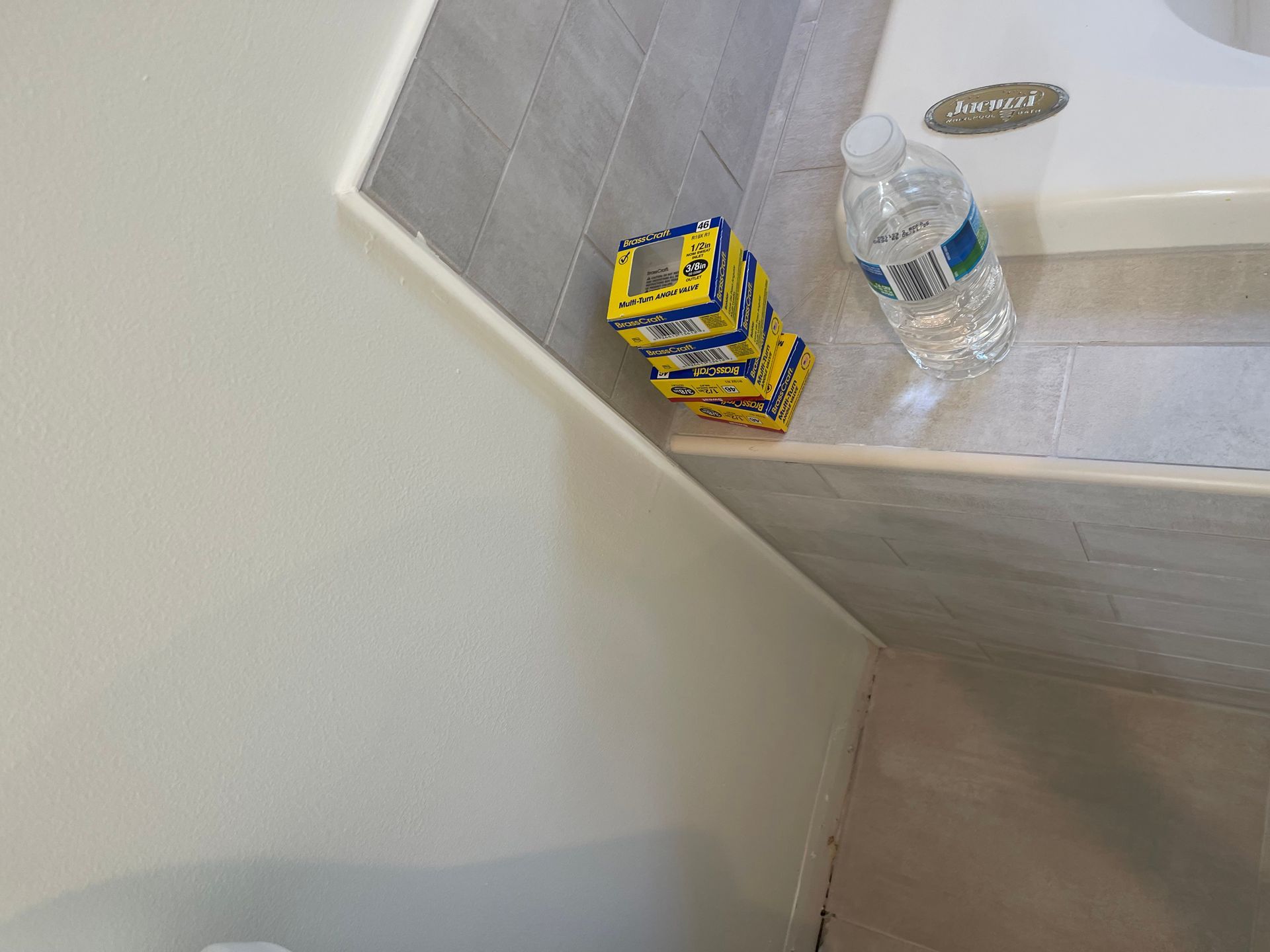 Yellow snack packs and a water bottle on a bathroom shelf beside a sink.