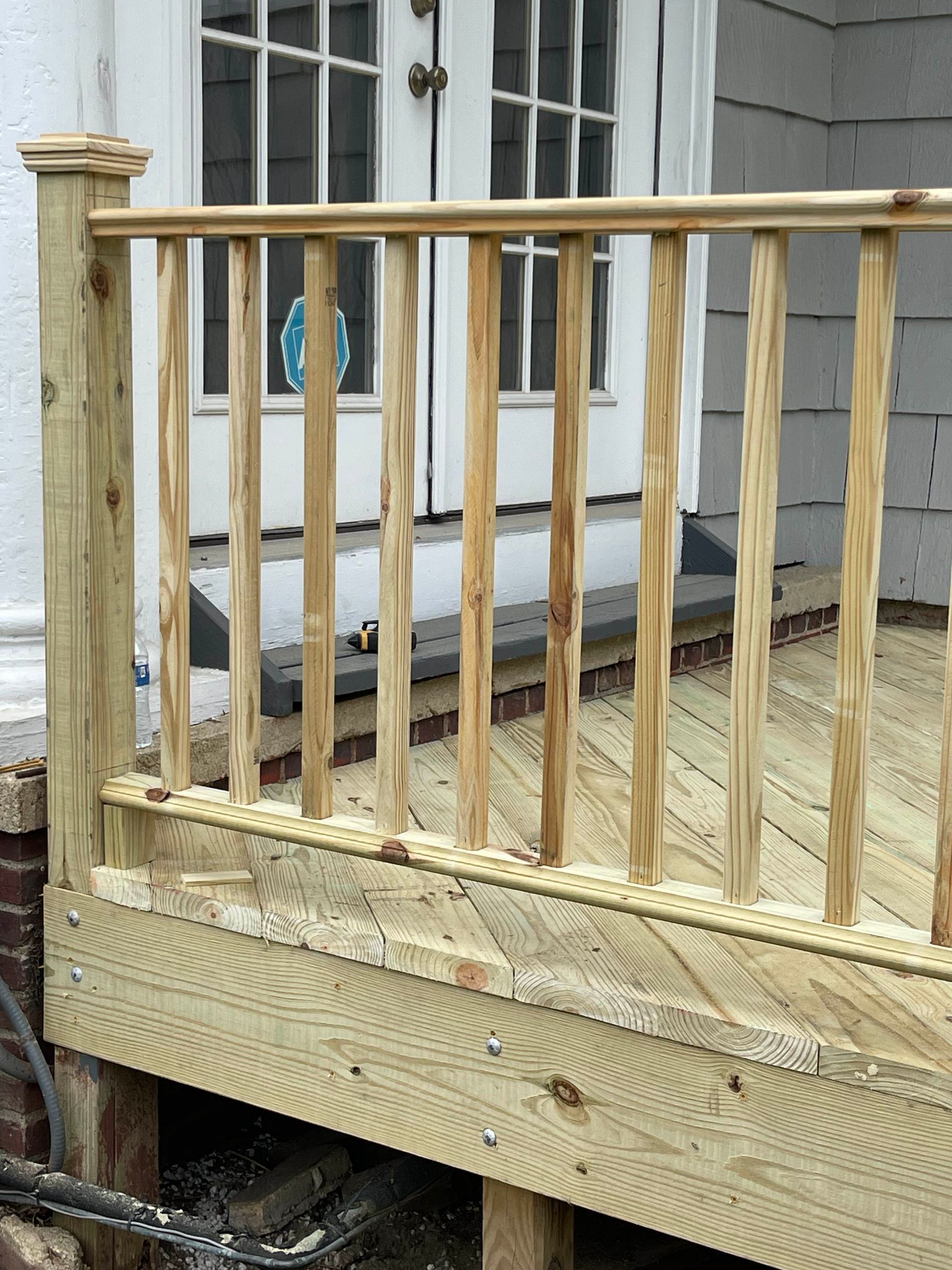 Wooden deck railing and steps beside white French doors with glass panes