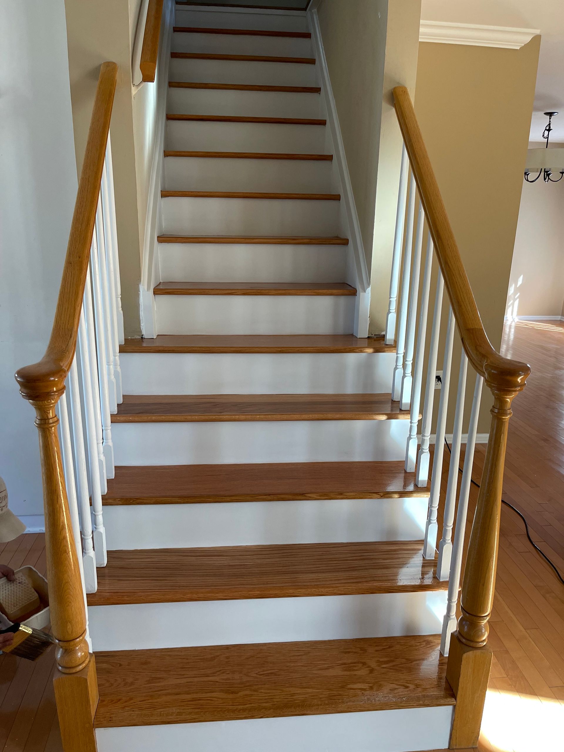 Wooden staircase with white risers and banister rails in a beige hallway