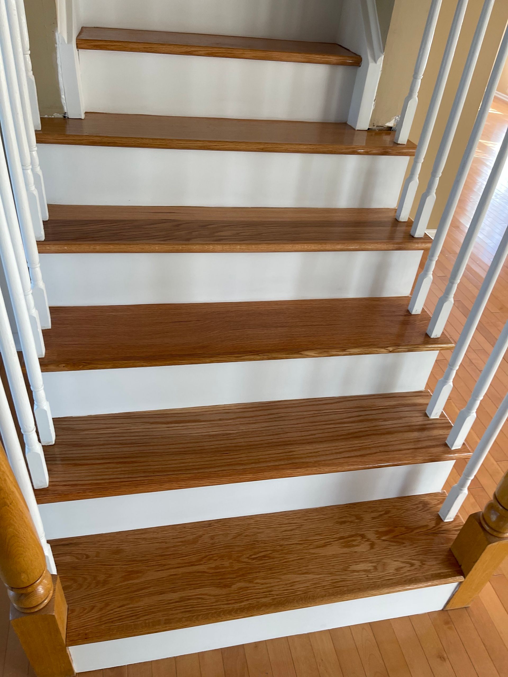 Wooden staircase with white risers and white railings indoors, viewed from the bottom up