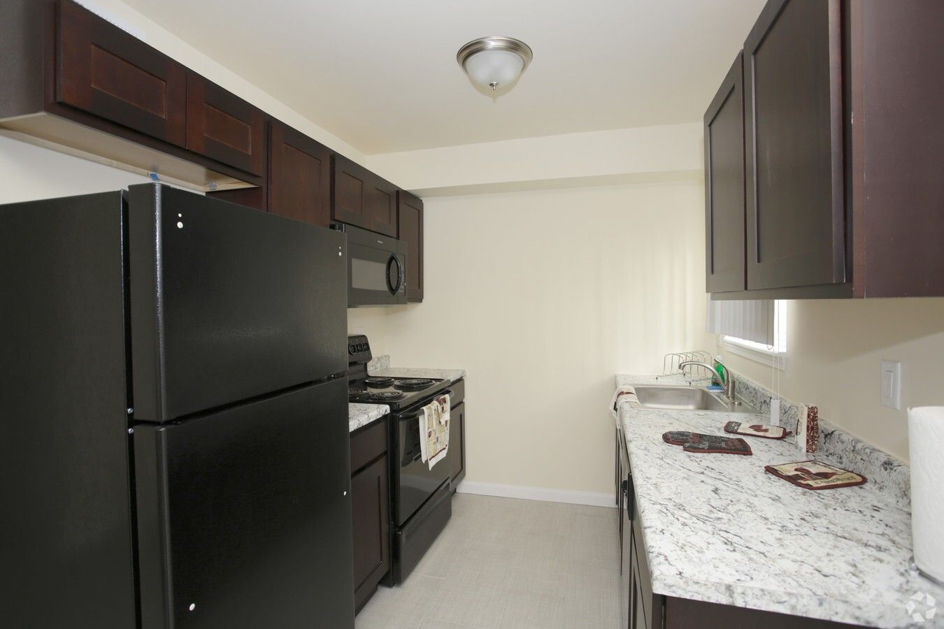 A kitchen with a black refrigerator , stove , sink and microwave.