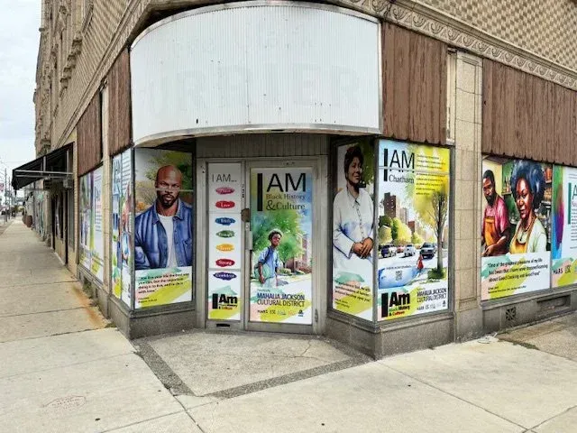 Corner storefront with promotional posters and a sidewalk along a brick building