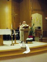 Priest at church altar with candles and white cloth draped on the steps