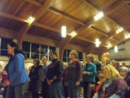 People standing in a church hall with a wooden vaulted ceiling during a gathering
