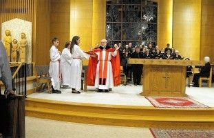 Catholic Mass at an altar, with a priest in red blessing congregants in a church.