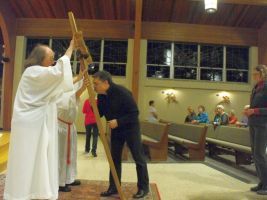 Priest blessing a man in a church during a ceremony, with pews and seated congregants in the background