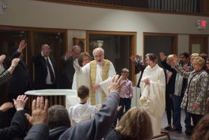 Religious ceremony with clergy and congregants in a church, people standing and raising hands near the altar