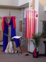 Clothes and robes hanging beside a striped curtain in an indoor display area.