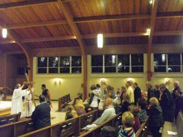 People gathered in a church sanctuary with wood beams and pews during a ceremony or service.