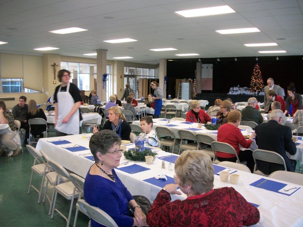 People seated at long tables in a banquet hall during a community meal or event