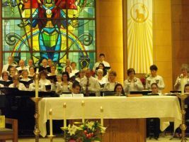Choir standing behind altar in a church with stained glass and candles