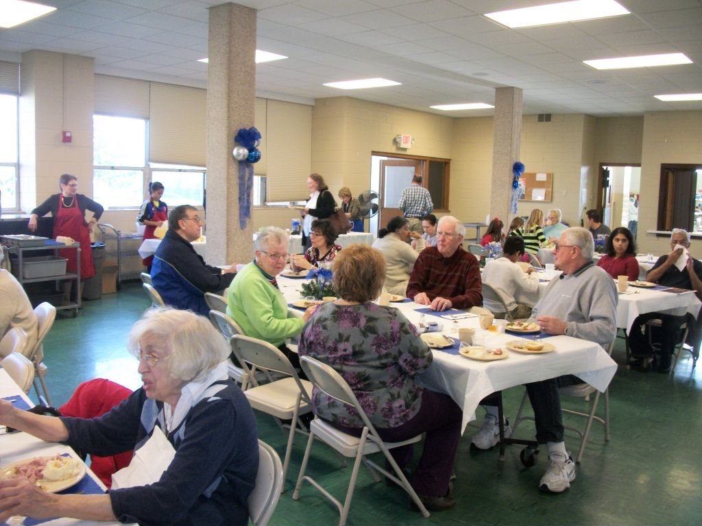 People seated at tables in a community hall during a social gathering