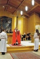 Church altar with a priest in red vestments and two white-robed altar servers