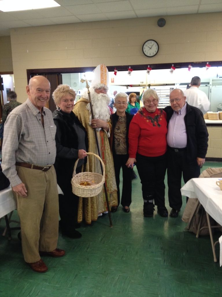 Group of people in costume posing indoors at a community event, one holding a basket.