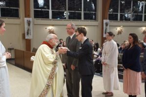 Priest blessing a line of people inside a church during a ceremony