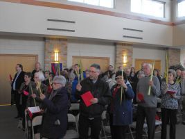 People holding colorful candles in a bright indoor hall, gathered in a group ceremony