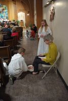 Two women in white and yellow outfits sit in a hallway while another person crouches beside them.