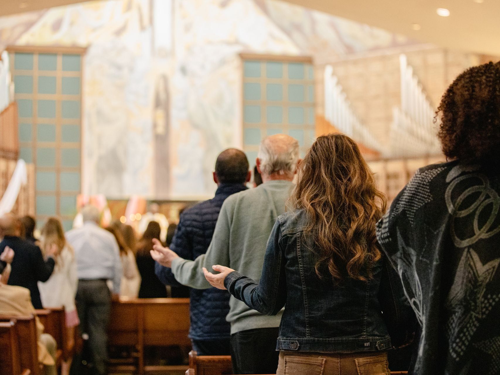 People standing in a church, facing the altar during a service.