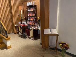 Ballet recital display with brochures beside a staircase and flower arrangement on carpeted floor