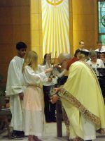 Clergy and altar servers during a church ceremony beneath a glowing sunburst backdrop