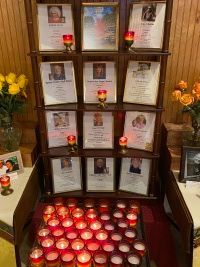 Memorial altar with framed photos, candles, and flowers arranged around a central display.