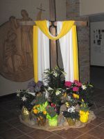 Decorated indoor memorial with yellow and white drapes and flowers at the base