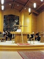 Church altar with candles and a cross, a person standing at the pulpit during a service