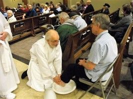 Man washing another man's feet in a church pew during a religious service