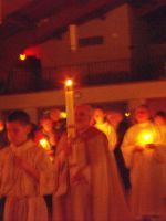 People holding lit candles in a dimly lit indoor procession or vigil