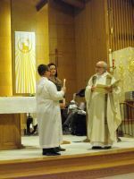 Two clergy in white robes stand at an altar during a church service.