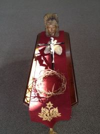Red coffin-shaped Christmas ornament with a Santa figure, wreath, and gold snowflake decoration