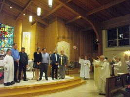 Church service with people standing near the altar in a wood-paneled sanctuary