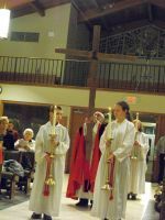 Clergy in white and red robes standing in a church aisle during a ceremony