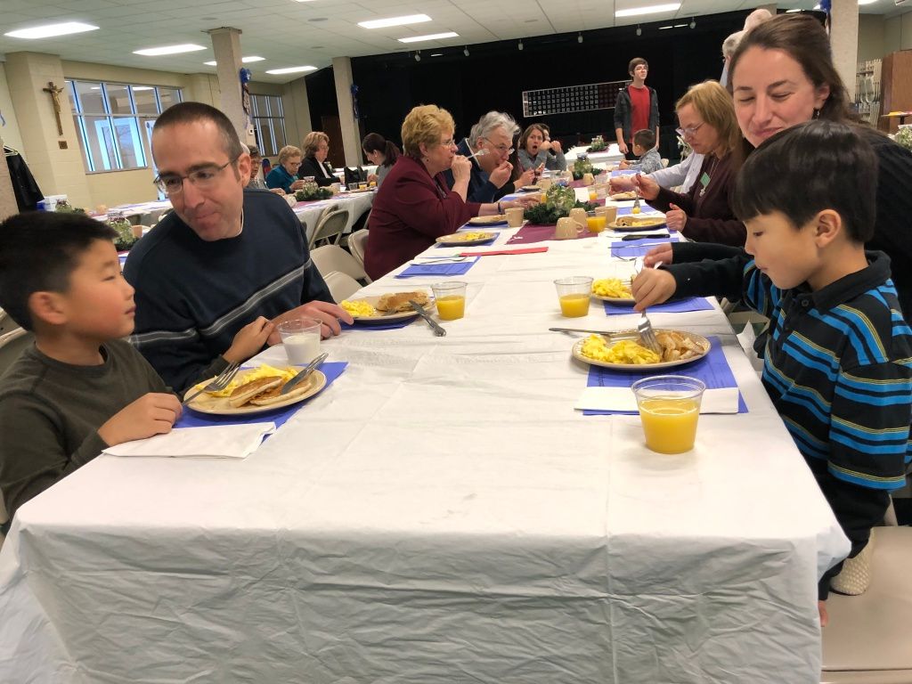 People seated at a long table sharing a meal in a bright community room