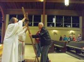 Two people in a church holding a wooden cross during a ceremony