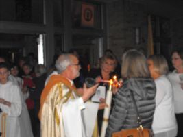 Candlelit church ceremony with a priest blessing attendees inside a dim sanctuary