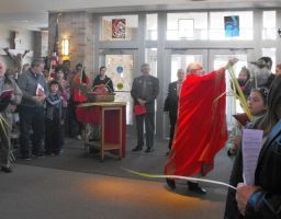 Indoor ceremony with a red cloth unveiling beside a gathered crowd