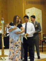Man holding a baby at a church ceremony with two others standing beside him