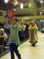 People dancing in a church hall, with a woman in a light blue sweater in the foreground.