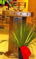 Wooden pulpit or lectern in a church, with a green palm arrangement and red cloth in front.