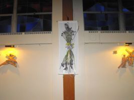 Flower bouquet tied to a wooden post between two lit wall sconces indoors