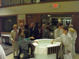 People gathered around a covered display table in a lobby or hallway.