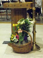 Floral arrangement in a wicker basket beside a brass lectern in a church interior
