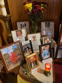 Memorial altar with framed photos, flowers, and a lit candle on a table