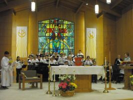 Church choir performing at altar with stained-glass window and floral arrangement
