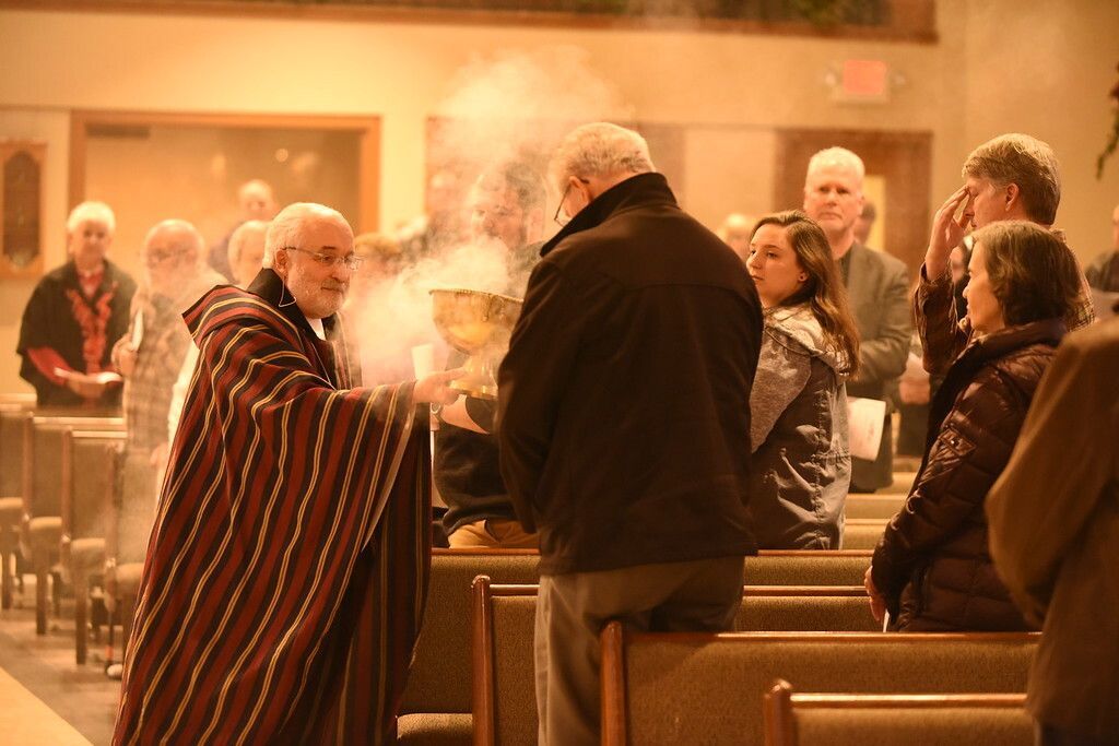 People in a church pew as smoke rises during a candlelit gathering